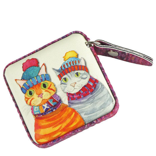 Quadratisches „Cats in Hats" Maßband von Emma Ball mit lila-rosa meliertem Rand. Aquarell-Illustration: orange Tigerkatze und graue Tabby in bunten Strickmützen und Schals.