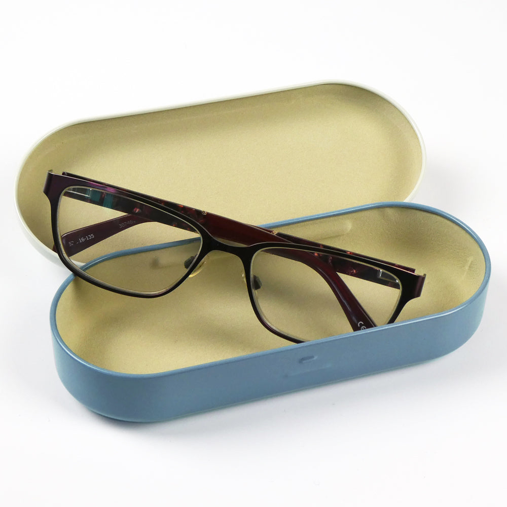Geöffnetes „Coastal Pieces" Etui von Emma Ball mit hellblauer Außenseite und beigem Filzfutter. Im Inneren liegt eine Brille mit dunkelrotem Rahmen.
