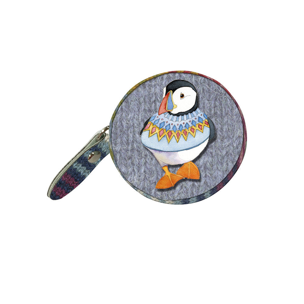 Geschlossenes „Woolly Puffins“ Maßband von Emma Ball auf weißem Hintergrund — rundes graublaues Gehäuse mit Papageientaucher in bunt gemustertem Strickpullover und seitlicher Lasche mit farbigem Strickmuster.