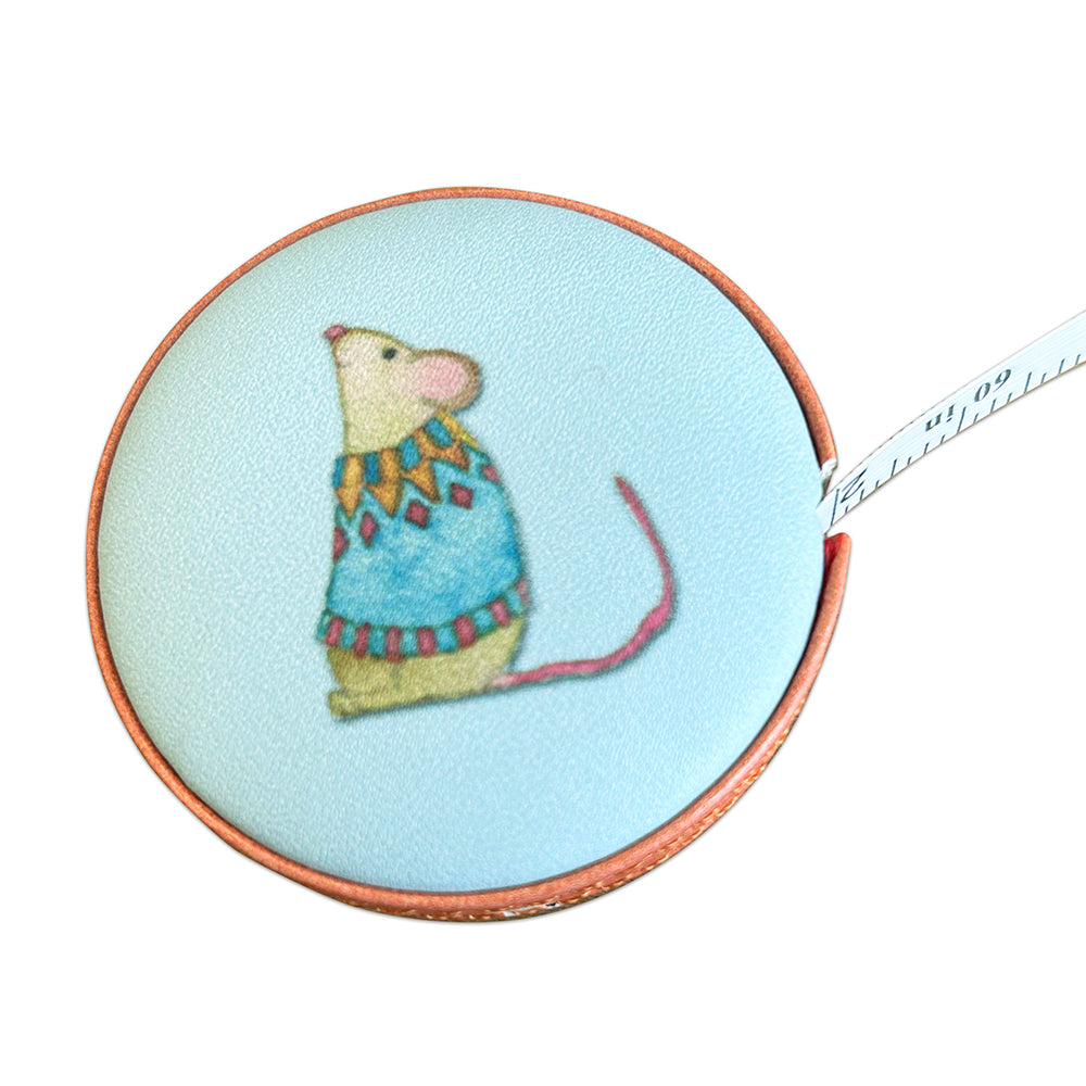 Rundes Maßband mit Aquarell-Illustration von Emma Ball: Maus im blau-gelben Strickpullover mit Fair-Isle-Muster auf hellblauem Hintergrund. Inch-Skala teilweise ausgezogen.