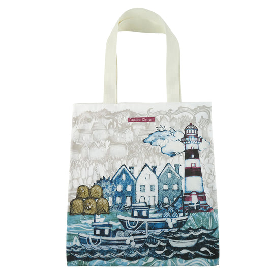 „Fishing Village" Tragetasche von Caroline Cleave auf weißem Hintergrund — großformatige Baumwoll-Canvas-Tasche mit rundum bedruckter Hafenszene: Fischerboote, Häuser, Leuchtturm; cremeweiße Webband-Henkel.