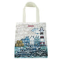 „Fishing Village" Tragetasche von Caroline Cleave auf weißem Hintergrund — großformatige Baumwoll-Canvas-Tasche mit rundum bedruckter Hafenszene: Fischerboote, Häuser, Leuchtturm; cremeweiße Webband-Henkel.